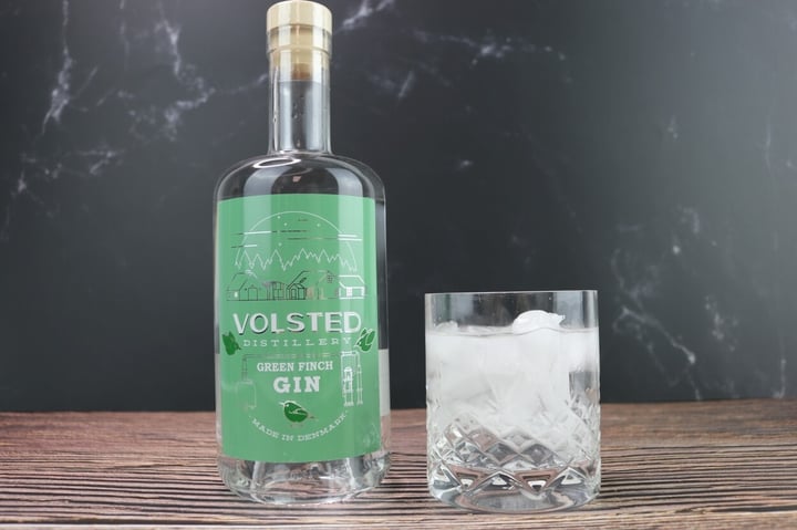 Volsted Distillery Green Finch gin på træbord med gin tonic ved siden af